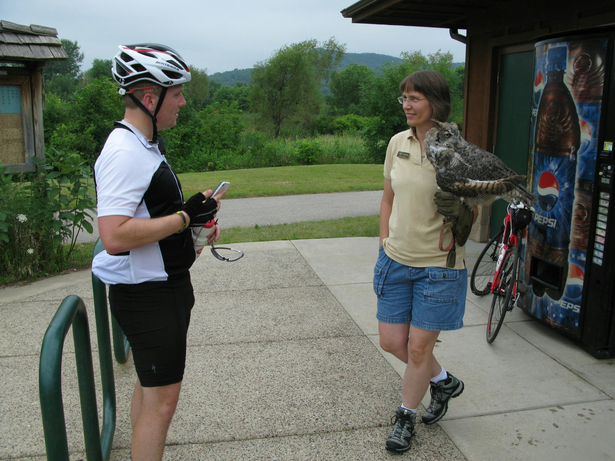 Karla Bloem, right, director of the Houston Nature Center, with Alice, a 16-year-old great horned owl, talks to cyclists on the Root River Trailhead in Houston, Minnesota. Left is Mike Mozer, 23, a Rochester resident and Mayo Clinic neuromuscular and cardiovascular scientist.