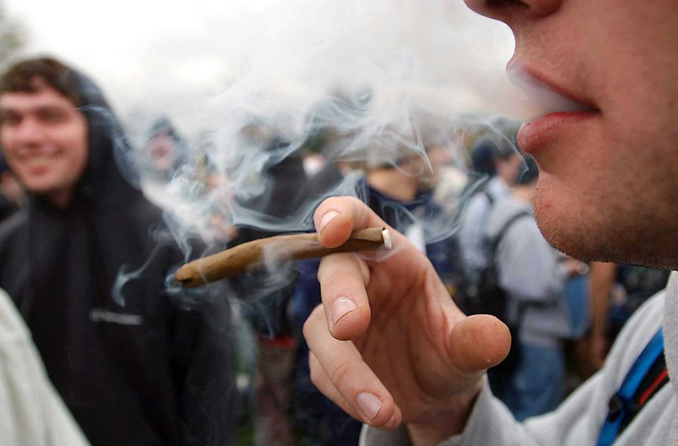 HOLD FOR MALCOLM RITTER STORY -- FILE - In an April 20, 2005 file photo, a University of Colorado freshman, who did not want to be identified, joins a crowd smoking marijuana during a "420" gathering at Farrand Field at the University of Colorado in Boulder, Colo. People who started using marijuana persistently before age 18 risk losing some of their IQ by the time they're 38, a long-running study says. In contrast, even long-term chronic users who started after age 18 showed no such effect, sug