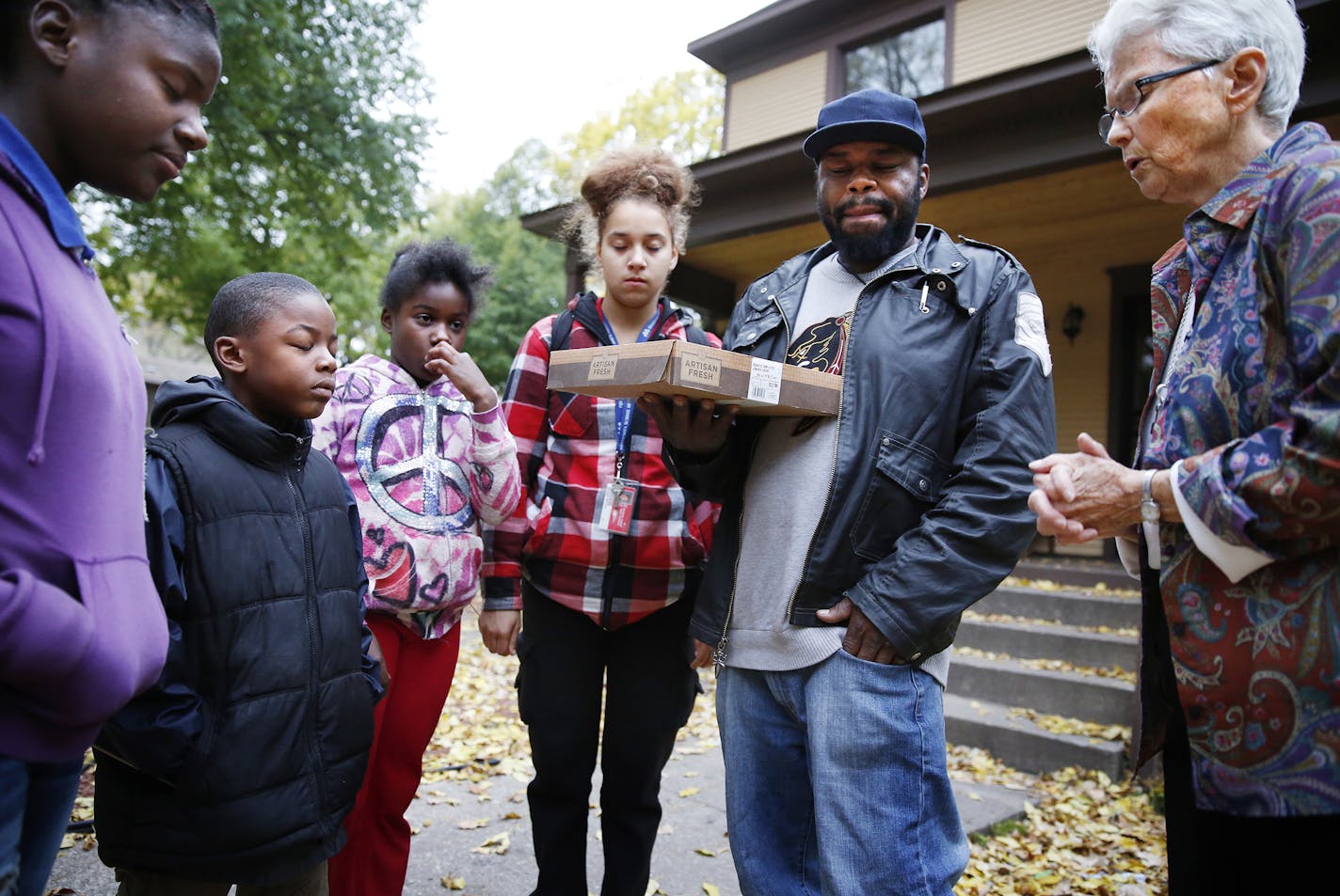 Sister Katherine Mullin, far right, prays with children outside their home who's brother was shot earlier that day in their neighborhood of North Minneapolis. From left is , Shamiya Coleman, 15, Tereveon Coleman, 7, Dejanae Coleman, 11, family friend Rayvon Minter, 16, and their uncle Rodney Coleman. ] LEILA NAVIDI leila.navidi@startribune.com / BACKGROUND INFORMATION: Monday, October 13, 2014. This year, the Visitation Monastery community of sisters celebrated the 25th anniversary of their mona