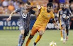 Minnesota United midfielder Ethan Finlay, left, is held back as Houston Dynamo defender Kevin Garcia, right, moves the ball during the first half of a