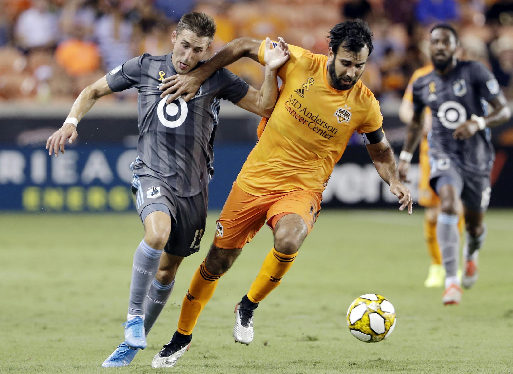 Minnesota United midfielder Ethan Finlay, left, is held back as Houston Dynamo defender Kevin Garcia, right, moves the ball during the first half of an MLS soccer match Wednesday, Sept. 11, 2019, in Houston. (AP Photo/Michael Wyke)