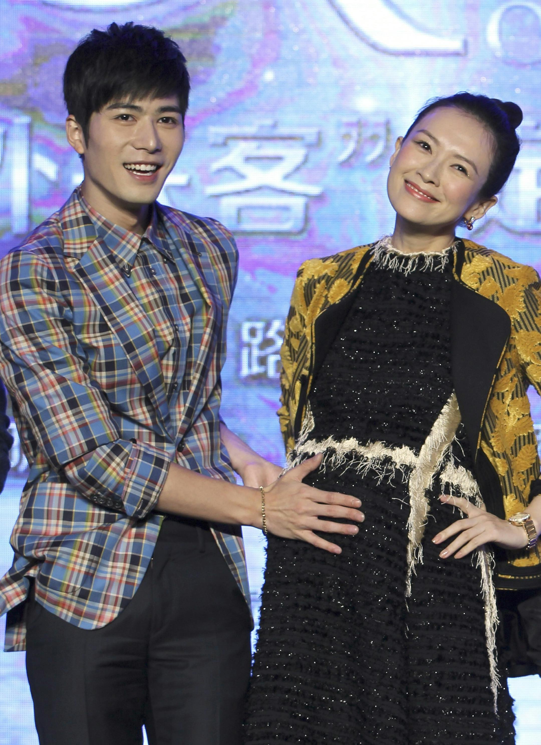 In this Aug. 4, 2015 photo, Chinese actor Chen Xuedong, left, touches the tummy of actress and co-producer Zhang Ziyi during a press conference of their new movie "Oh My God" in Beijing. Zhang, who gained international fame for her role in "Crouching Tiger, Hidden Dragon," posted a photo of a baby's hand online Monday, Dec. 28, 2015, to announce the arrival of her daughter. (Chinatopix via AP) CHINA OUT