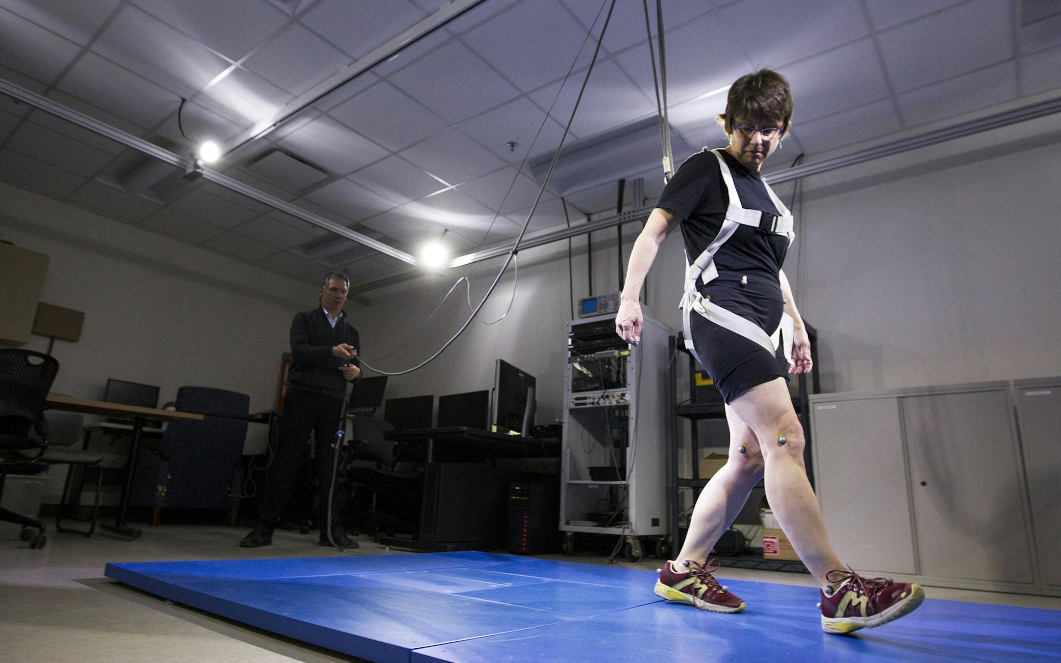 Dr. Colum MacKinnon, demonstrates how volunteer Liz Ogren's gait is tested with reflective markers, high speed cameras, muscle sensors, and weight-sensitive flooring at the University of Minnesota in Minneapolis April 25, 2014. Edina resident Ogren was diagnosed with Parkinson's disease in 2007. (Courtney Perry/Special to the Star Tribune)