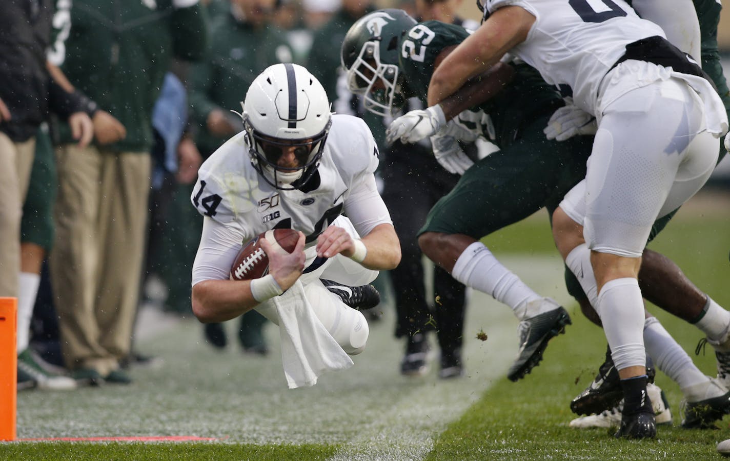 Penn State quarterback Sean Clifford, left, dives for a first down against Michigan State.