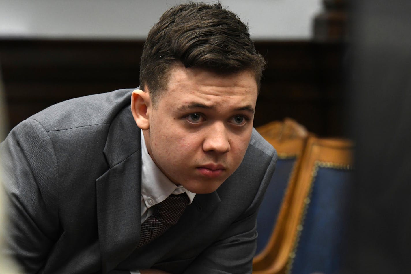 Kyle Rittenhouse peers at the screen as attorneys for both sides argue about a video during Rittenhouse's trial at the Kenosha County Courthouse in Kenosha, Wis., on Friday, Nov. 12, 2021. Rittenhouse is accused of killing two people and wounding a third during a protest over police brutality in Kenosha, last year. (Mark Hertzberg /Pool Photo via AP)