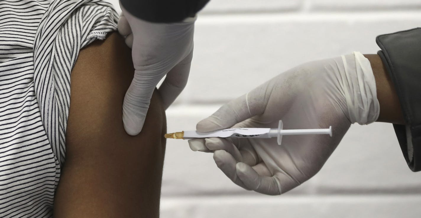 A vaccine volunteer receives an injection at the Chris Hani Baragwanath hospital in Soweto, Johannesburg Wednesday, June 24, 2020. Africa's first participation in a COVID-19 vaccine trial has begun as volunteers received injections developed at the University of Oxford in Britain. The large-scale trial is being conducted in South Africa, Britain and Brazil. (AP Photo/Siphiwe Sibeko)