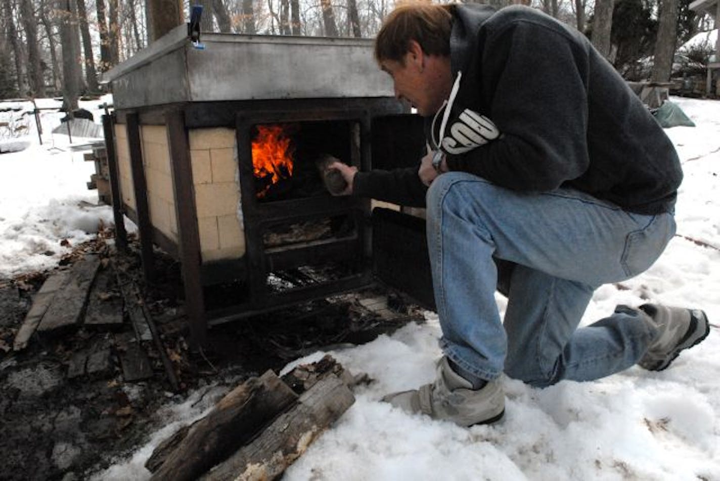 Lon Navis stokes the cooker he uses each spring to boil sap into maple syrup. Navis and his neighbors boil 300 gallons or more of sap.