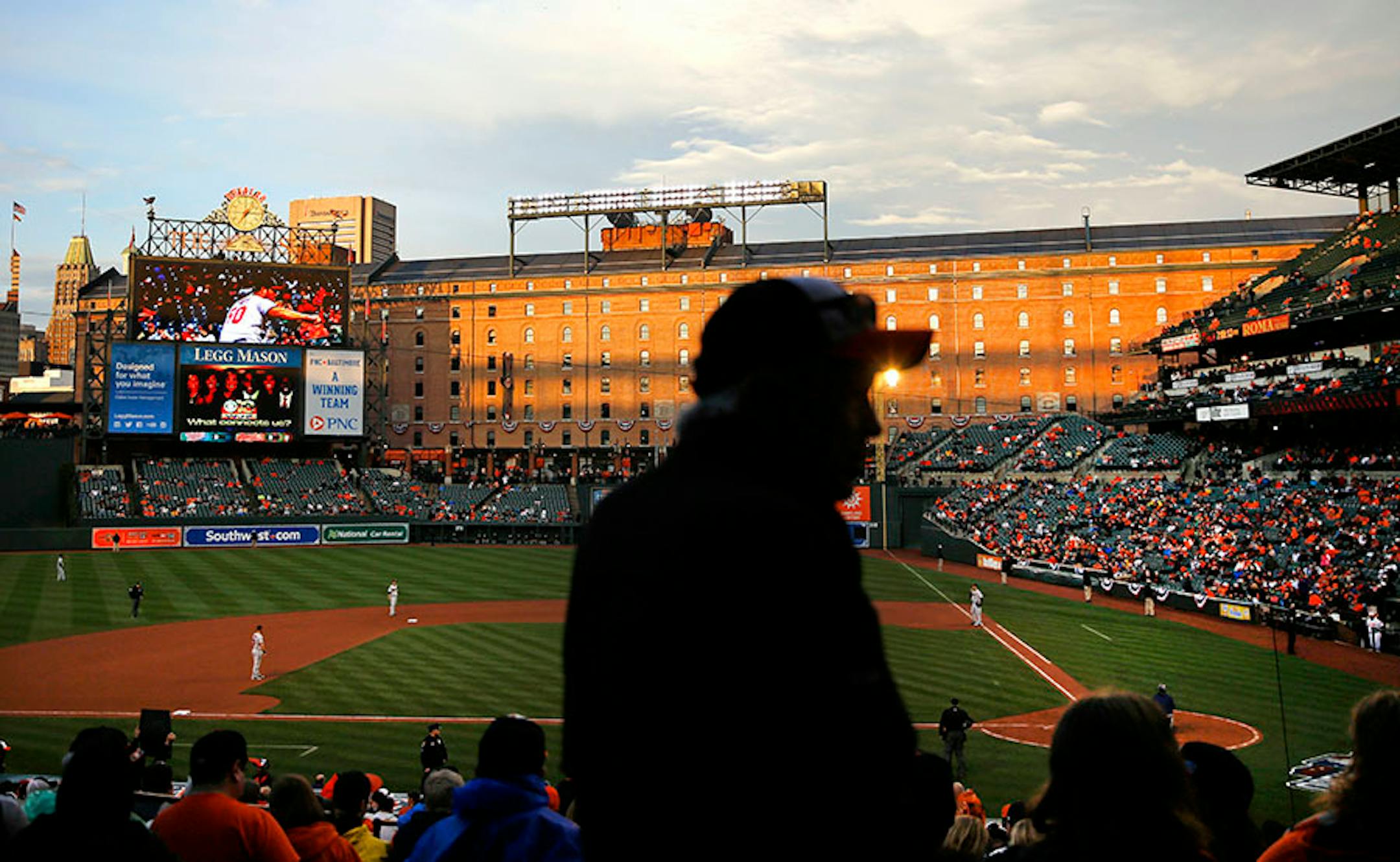 The sun sets against the B&O Warehouse behind right during an opening day baseball game between the Baltimore Orioles and the Minnesota Twins in Baltimore, Monday, April 4, 2016. (AP Photo/Patrick Semansky)