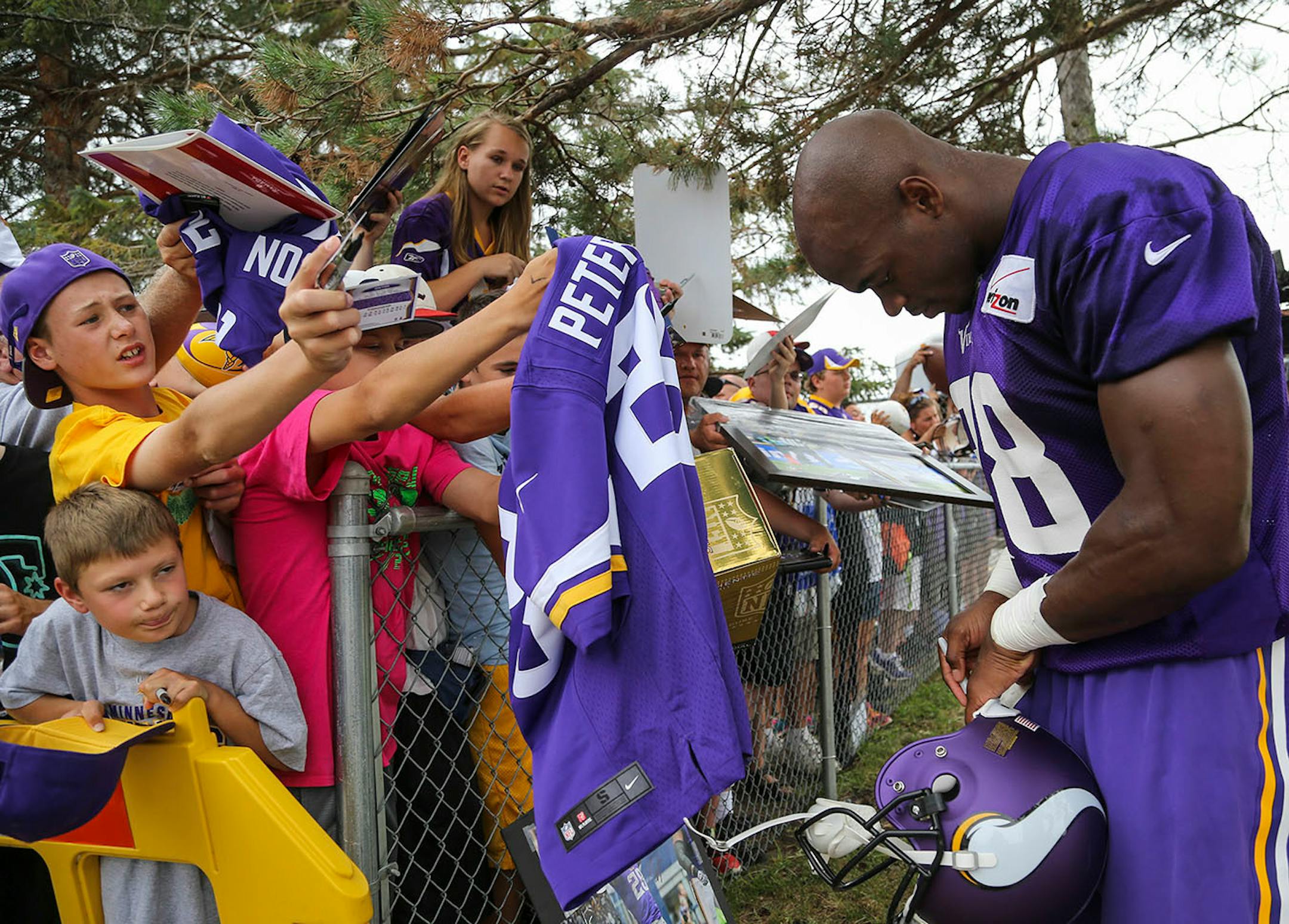 Adrian Peterson signs autographs after the afternoon session of training camp Friday, July 24, 2014, at Mankato State University.
