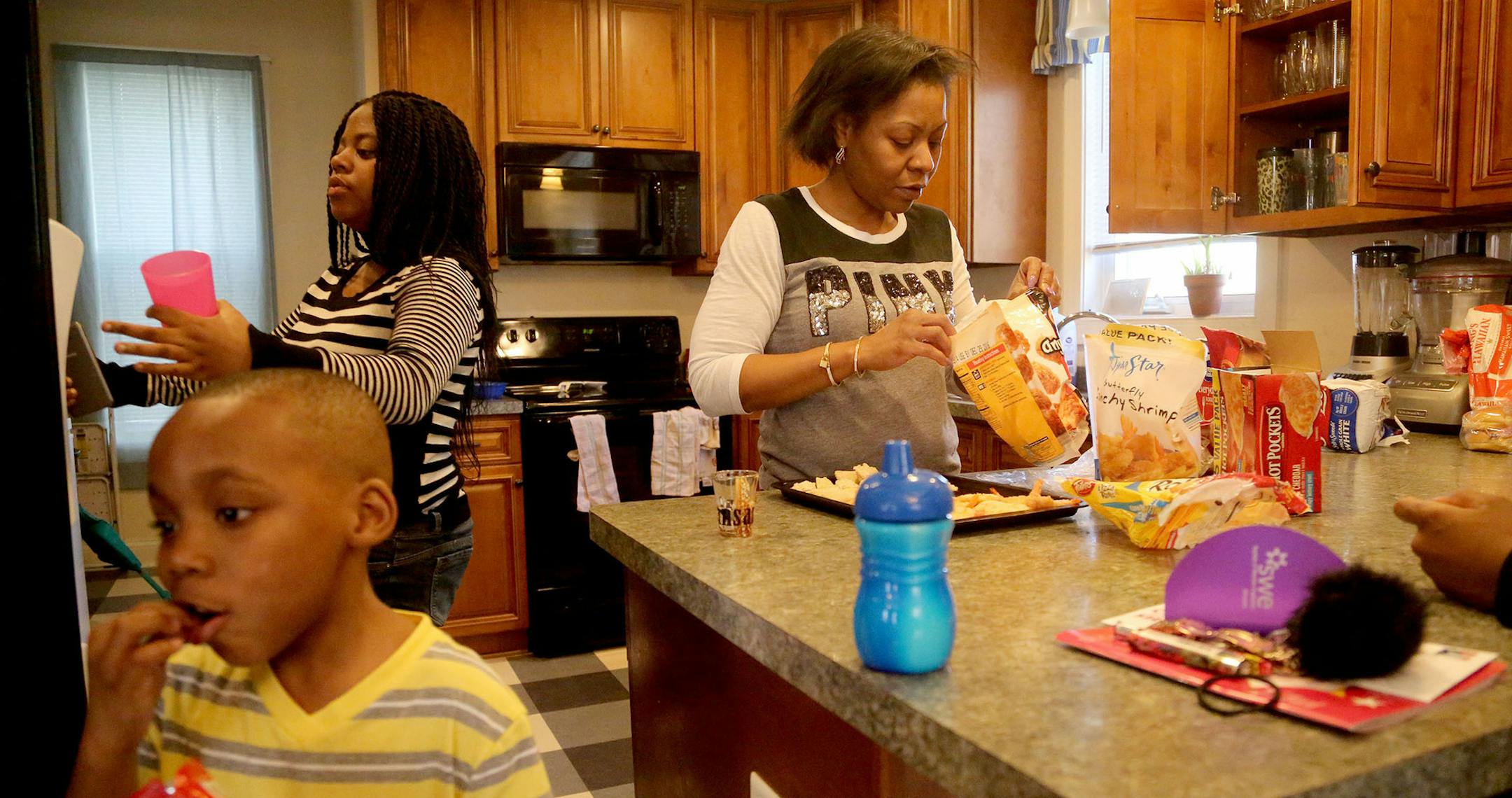 Ethrophic Burnett grew up in the projects of Chicago and came to Minneapolis in 1997 with her oldest and pregnant with her second child, to seek a better life. Here, Ethrophic Burnett works on lunch as her children Jeremiah, front, and Aaliyah get snacks and drinks before an outing at a local roller rink Saturday, April 25, 2016, in North Minneapolis, MN. In 2000, after the Hollman lawsuit, which attempted to integrate the suburbs, Burnett and her children wound up in Chaska. The change was diff
