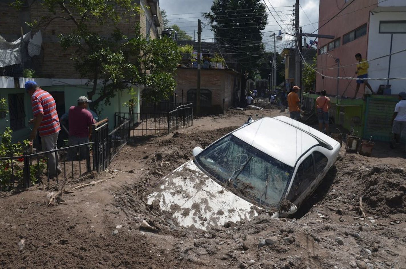 A car lays buried in mud after flooding triggered by Tropical Storm Manuel as residents try to clean up their neighborhood in Chilpancingo, Mexico, Thursday, Sept. 19, 2013.