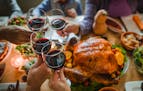 Guests toasting with wine during Thanksgiving dinner at dining table.