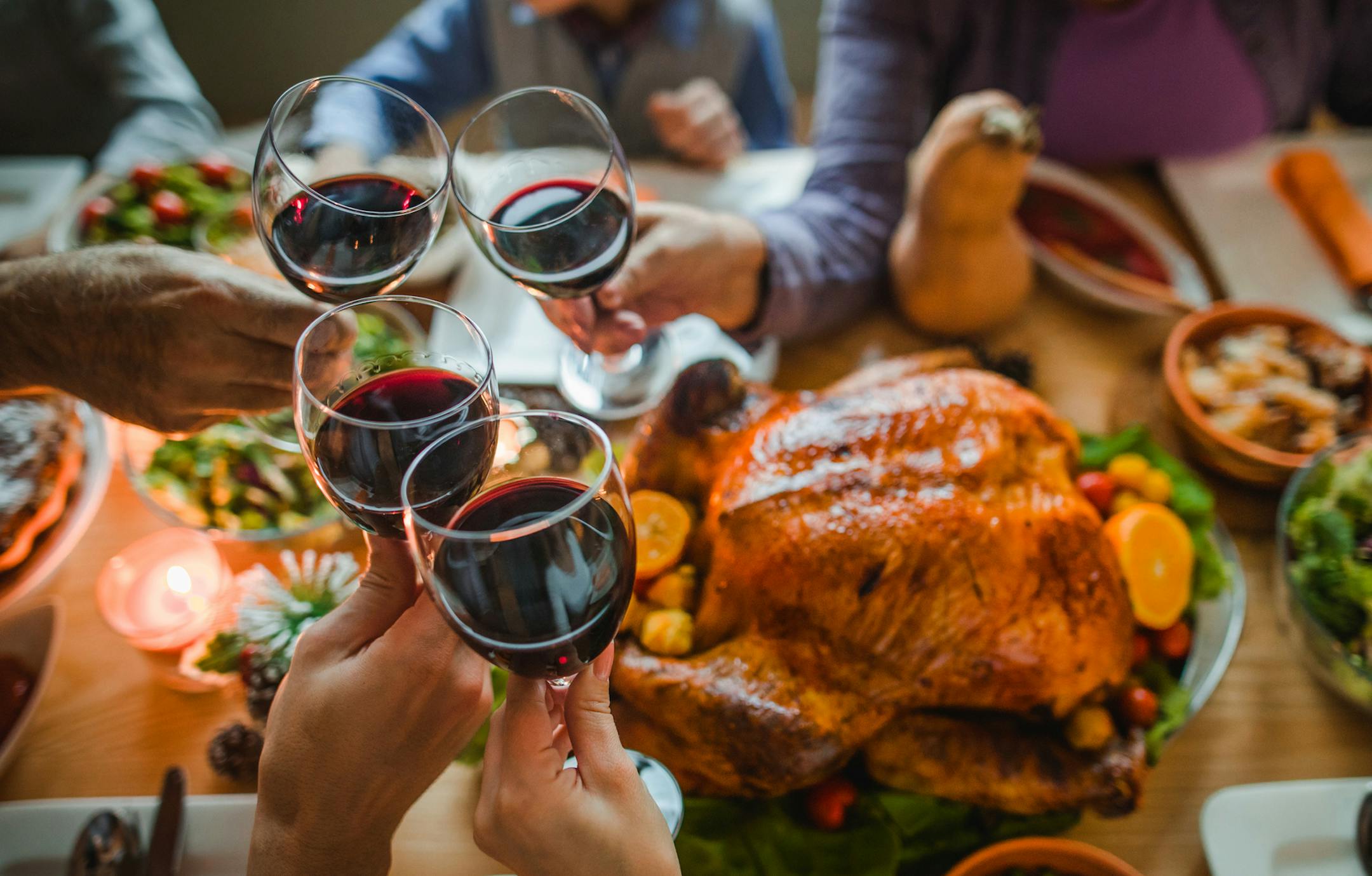 Guests toasting with wine during Thanksgiving dinner at dining table.