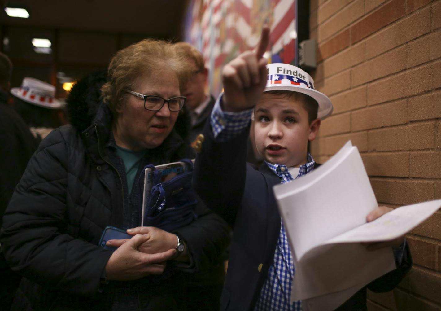 Volunteer precinct finder Keaton Leithead, 13, directed Nancy Schaffert of Eagan to her caucus at Black Hawk Middle School Tuesday night. ] JEFF WHEELER &#xef; jeff.wheeler@startribune.com Eagan and Burnsville residents gathered to attend their precinct caucuses at Black Hawk Middle School Tuesday evening, March 1, 2016.