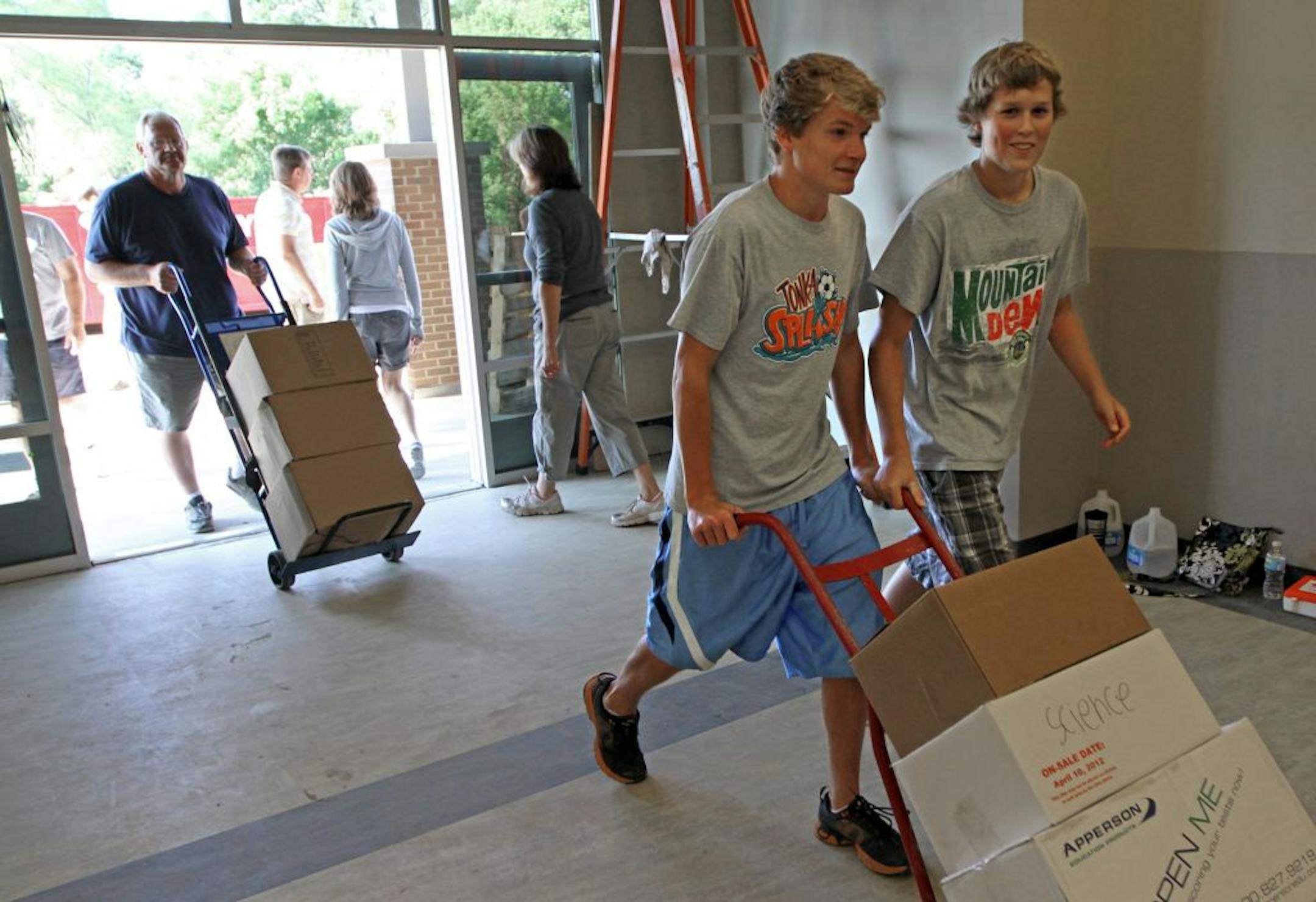 (left to right) Southwest Christian High students Joey Gasper and Hunter Crawford helped wheel boxes into their new school during moving day. Southwest Christian High, after 16 years of shuffling between temporary locations in the west metro, is getting a new school, set to open September 4th. in Chaska. Parents, administrators and students moved the school, currently located in the Nordic Track factory in Chaska's industrial park, to their new digs about three miles down the road, just on the o