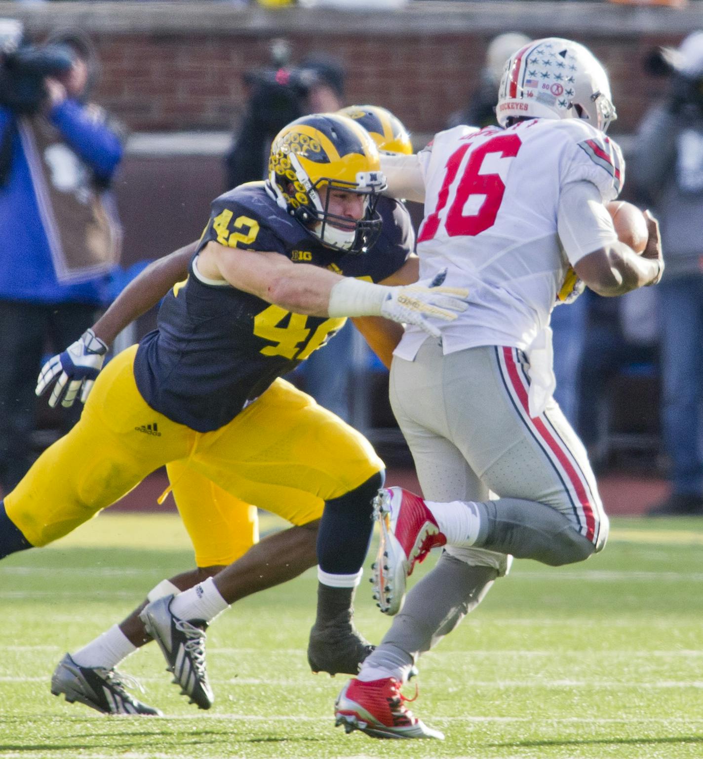 Michigan linebacker Ben Gedeon (42) pressures Ohio State quarterback J.T. Barrett (16) in the fourth quarter of an NCAA college football game in Ann Arbor, Mich., Saturday, Nov. 28, 2015. Ohio State won 42-13. (AP Photo/Tony Ding)