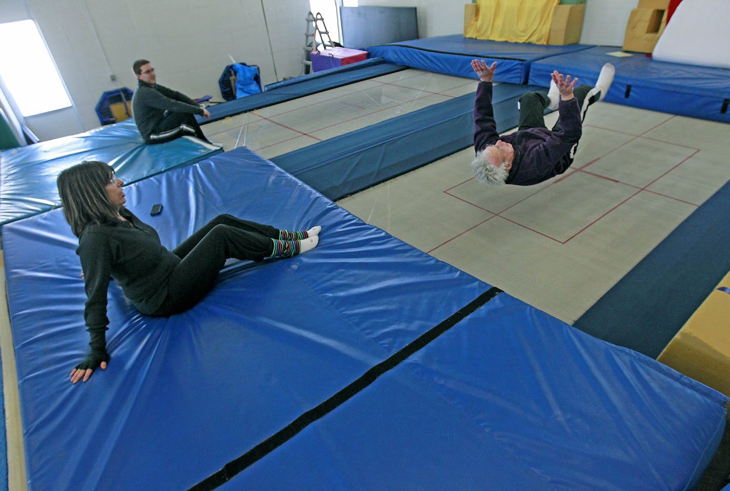 Under the watchful eye of his grandson Michael Royce, left, and daughter Cindy Royce, center, Elliott Royce e took trampoline lessons at Minnesota Twisters, Tuesday, February 25, 2015 in Edina, MN. Royce estimates that he has fallen down at least 14,000 times. He's not clumsy; he's doing it on purpose. He teaches people -- primarily seniors -- how to fall safely if they are undone by slippery sidewalks. ] (ELIZABETH FLORES/STAR TRIBUNE) ELIZABETH FLORES &#x2022; eflores@startribune.com