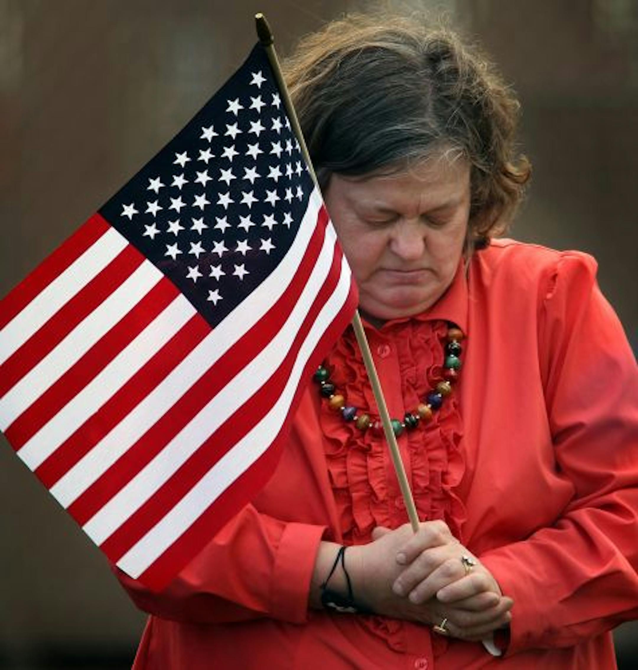 Sally Minars of St. Cloud bowed her head during the invocation at the opening of the Central Minnesota Tea Party Rally at Eastman Park in St. Cloud on Saturday. Minars said that she is not a Tea Party member, but that "God must have led me here today."