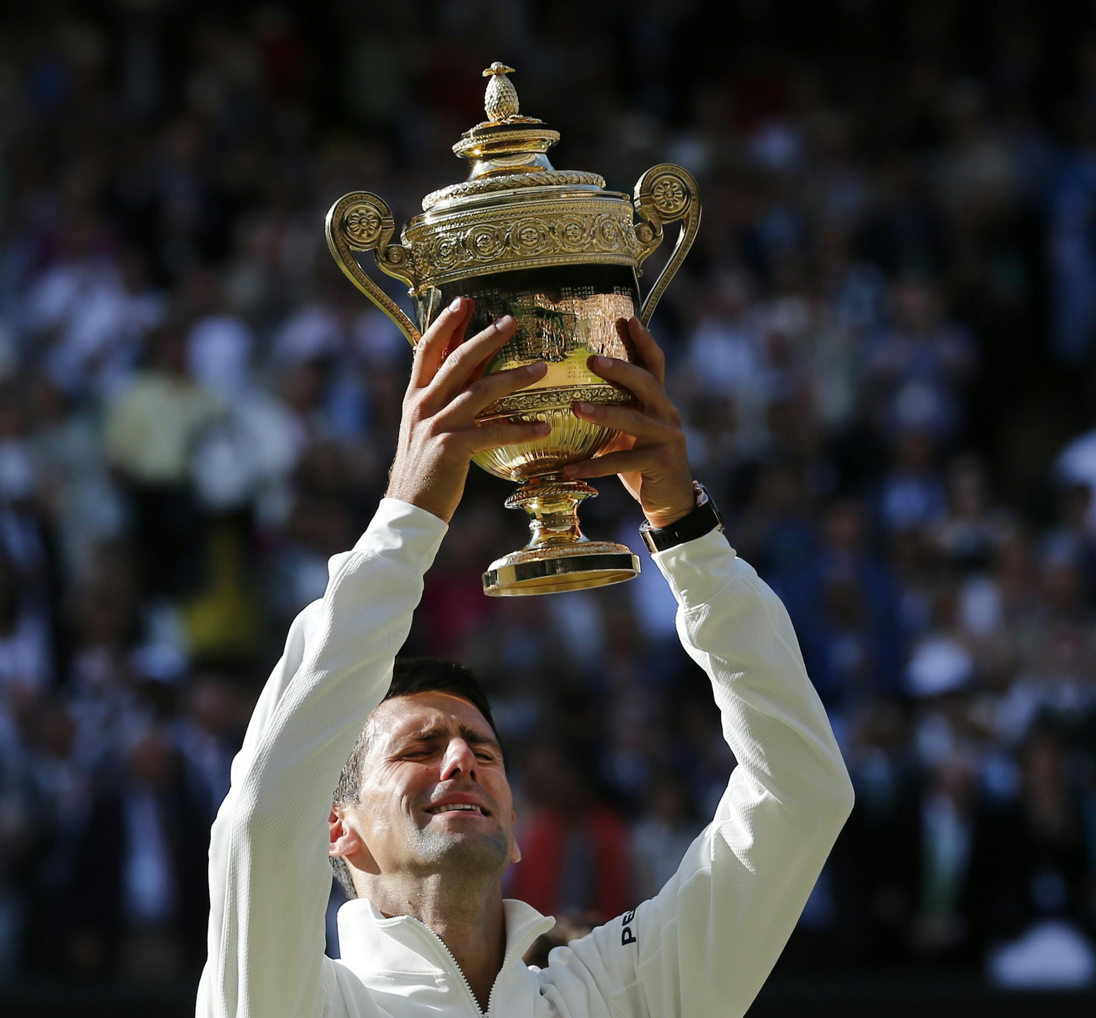 Novak Djokovic of Serbia holds up the trophy after defeating Roger Federer of Switzerland in the men's singles final at the All England Lawn Tennis Championships in Wimbledon, London, Sunday July 6, 2014. (AP Photo/Ben Curtis)