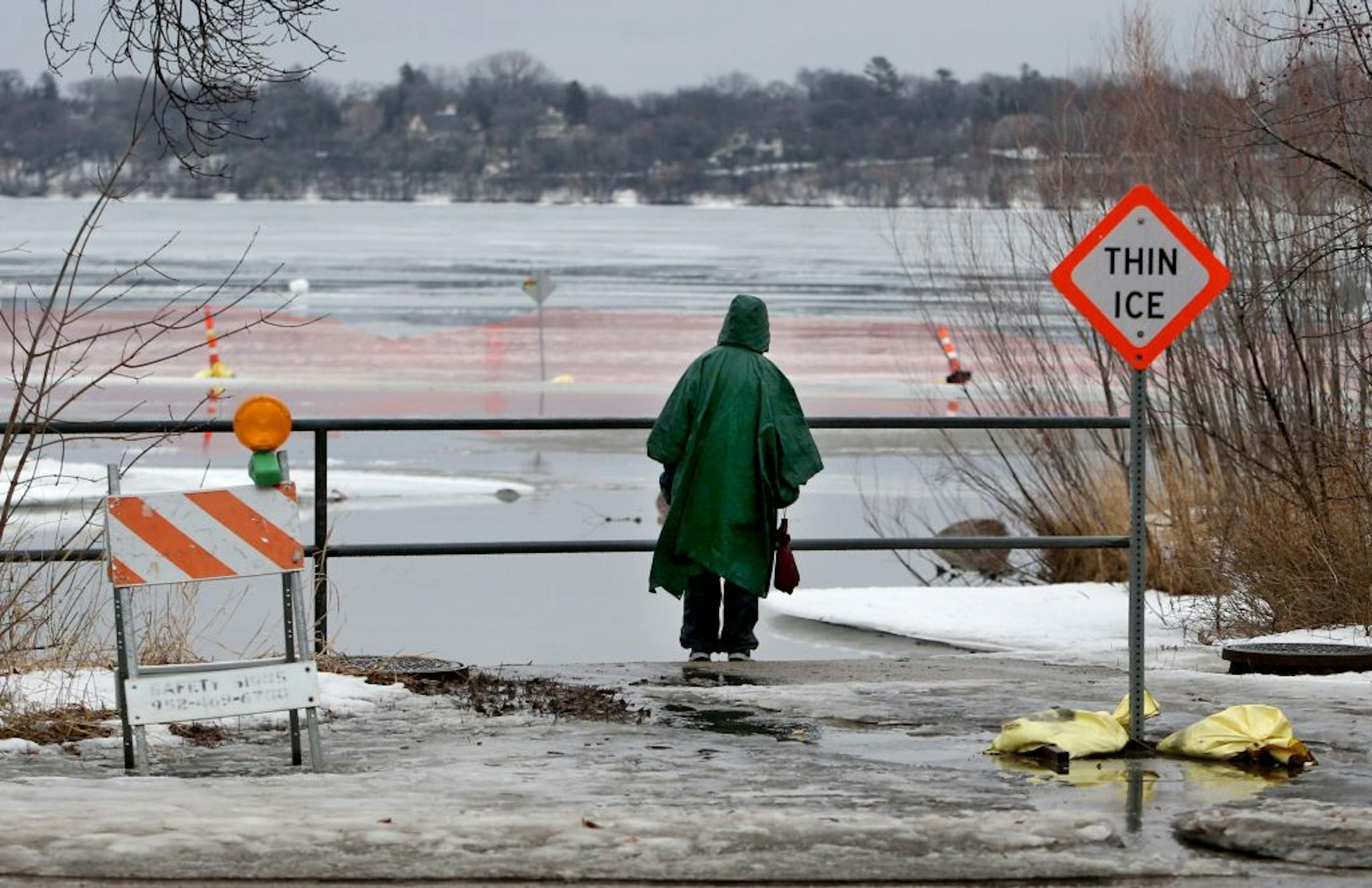 A pedestrian checks out the ice melt on Lake Harriet after a morning of warm temps and rain Friday, Feb. 19, 2016, in Minneapolis, MN.