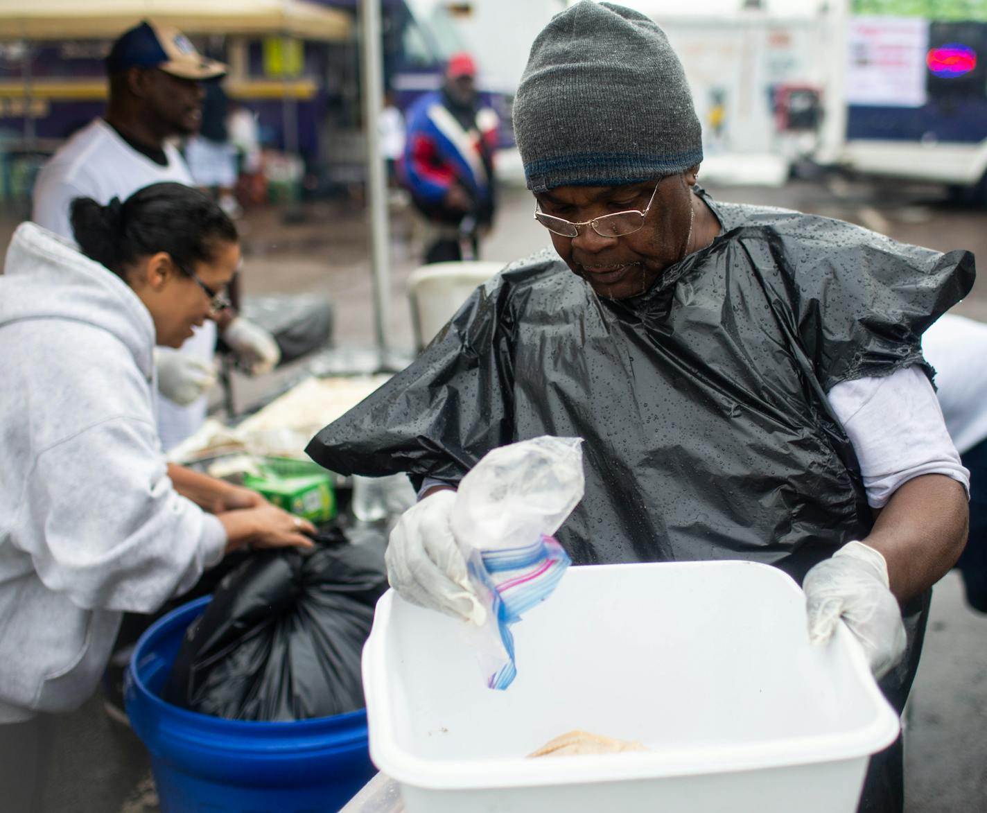 Clark Adams tries to stay dry while he helps prepare chicken for T Jax Smoke Stack in the rain. ] NICOLE NERI &#x2022; nicole.neri@startribune.com BACKGROUND INFORMATION: The Rondo Days festival continued despite the rain and the parade's cancellation Saturday, July 20, 2019.