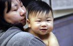 Able Zhang, 1, smiles after receiving the last of three inoculations, including a vaccine for measles, mumps, and rubella (MMR), as his mother Wenyi Z