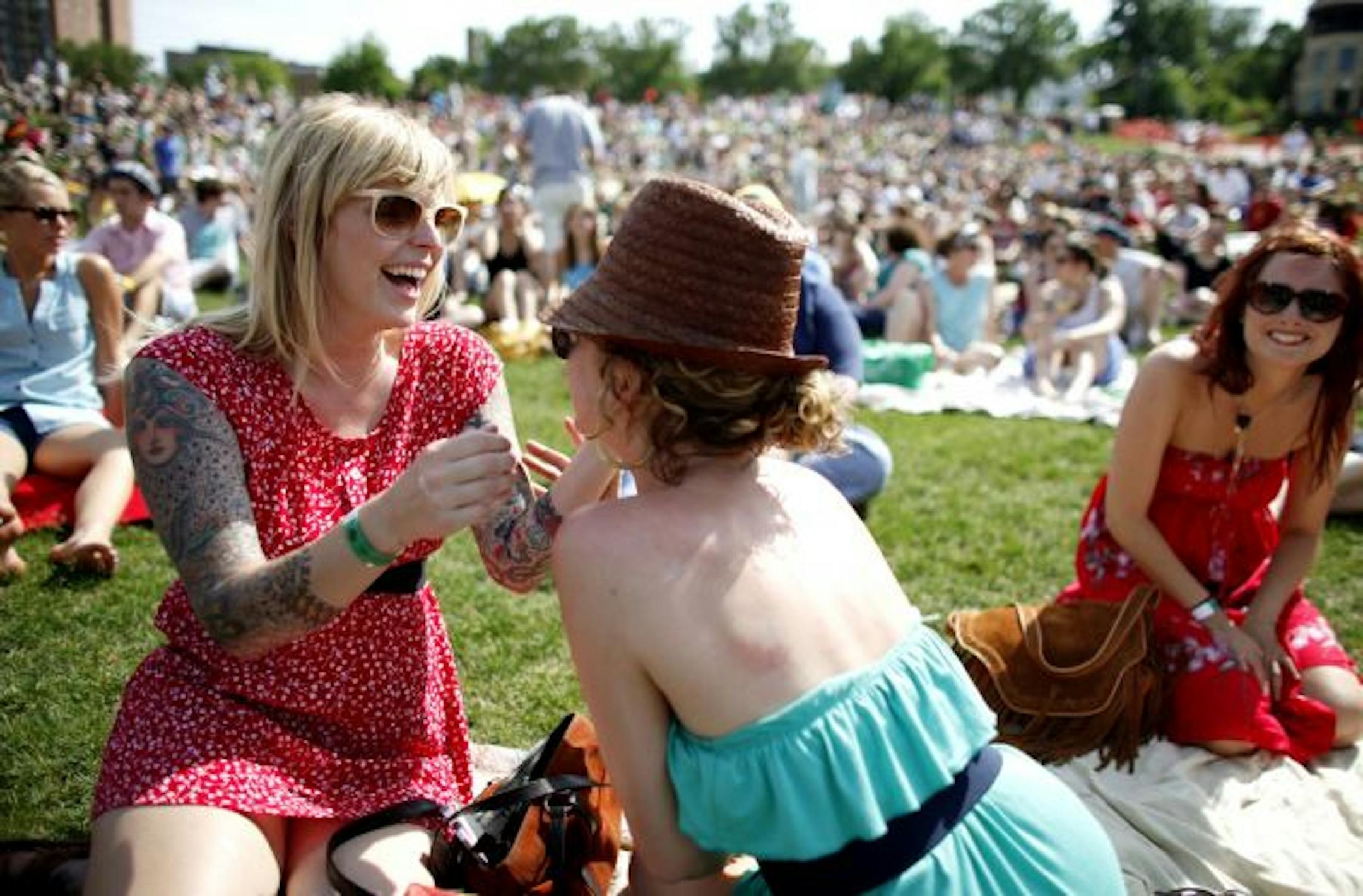 Olivia Brown, left, helps Therese LIttle, center, both of Minneapolis, put on sunblock prior to the band Solid Gold performance during the Rock the Garden concert Saturday afternoon at the Walker Art Center in Minneapolis.
