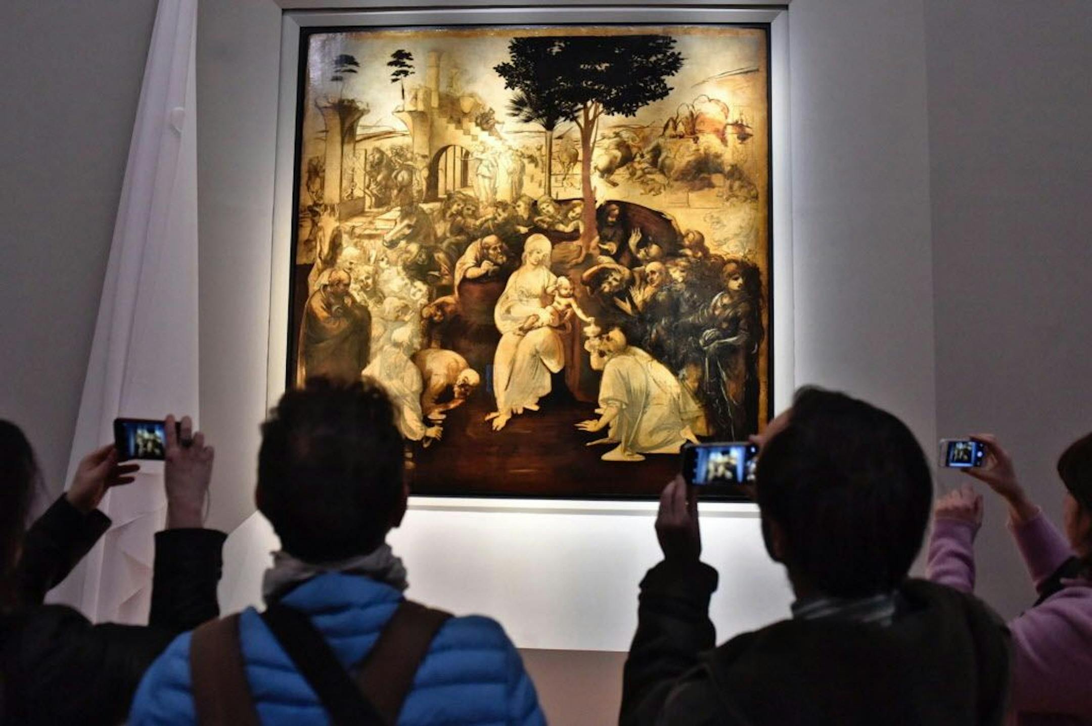 Visitors take pictures of Leonardo da Vinci's "Adoration of the Three Wise Men", returned to the public of the Uffizi museum after 6 years of study and restoration, in Florence, Italy, Monday, March 27, 2017. Painted in 1481, it is one of the most important works of the early Leonardo.