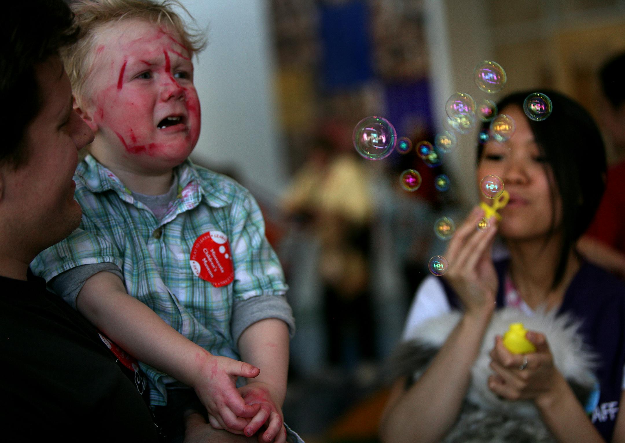 Children's Museum staffer Regina Santiago, right, blew bubbles toward Drake Johnsrud to help him settle down. The museum is now training museum leaders nationally in the technique.