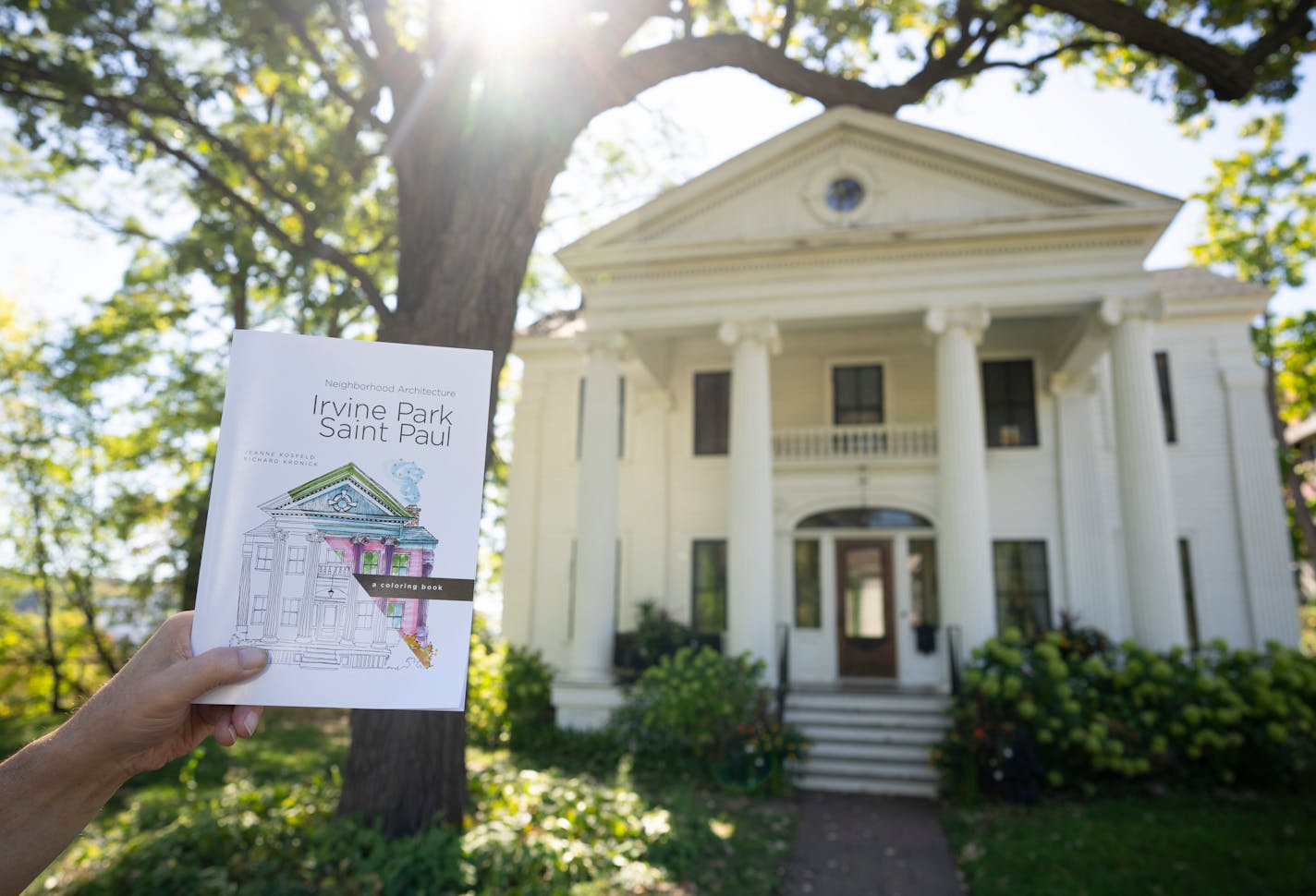 Richard Kronick held up the architectural history of Irvine Park disguised as a coloring book outside the 1851 Greek Revival house in Irvine Park (with a Colonial Revival porch added in 1906) featured on the cover of the book he did with the artist Jeanne Kosfeld. ] JEFF WHEELER • jeff.wheeler@startribune.com