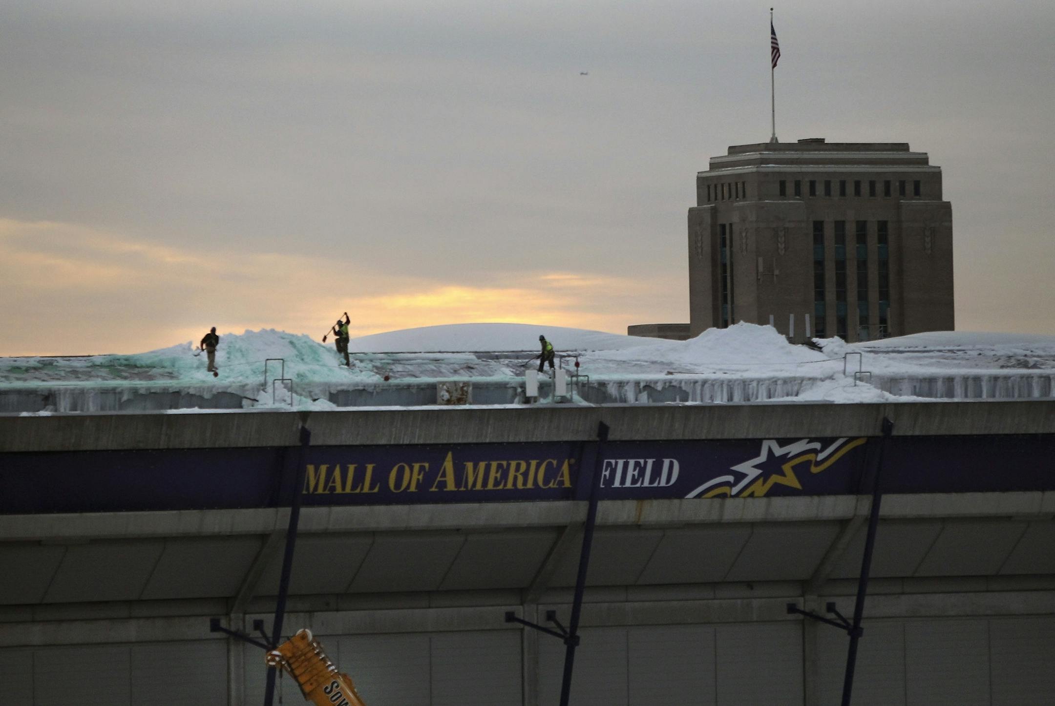 Crew work on shoveling snow from the dome early Tuesday morning.