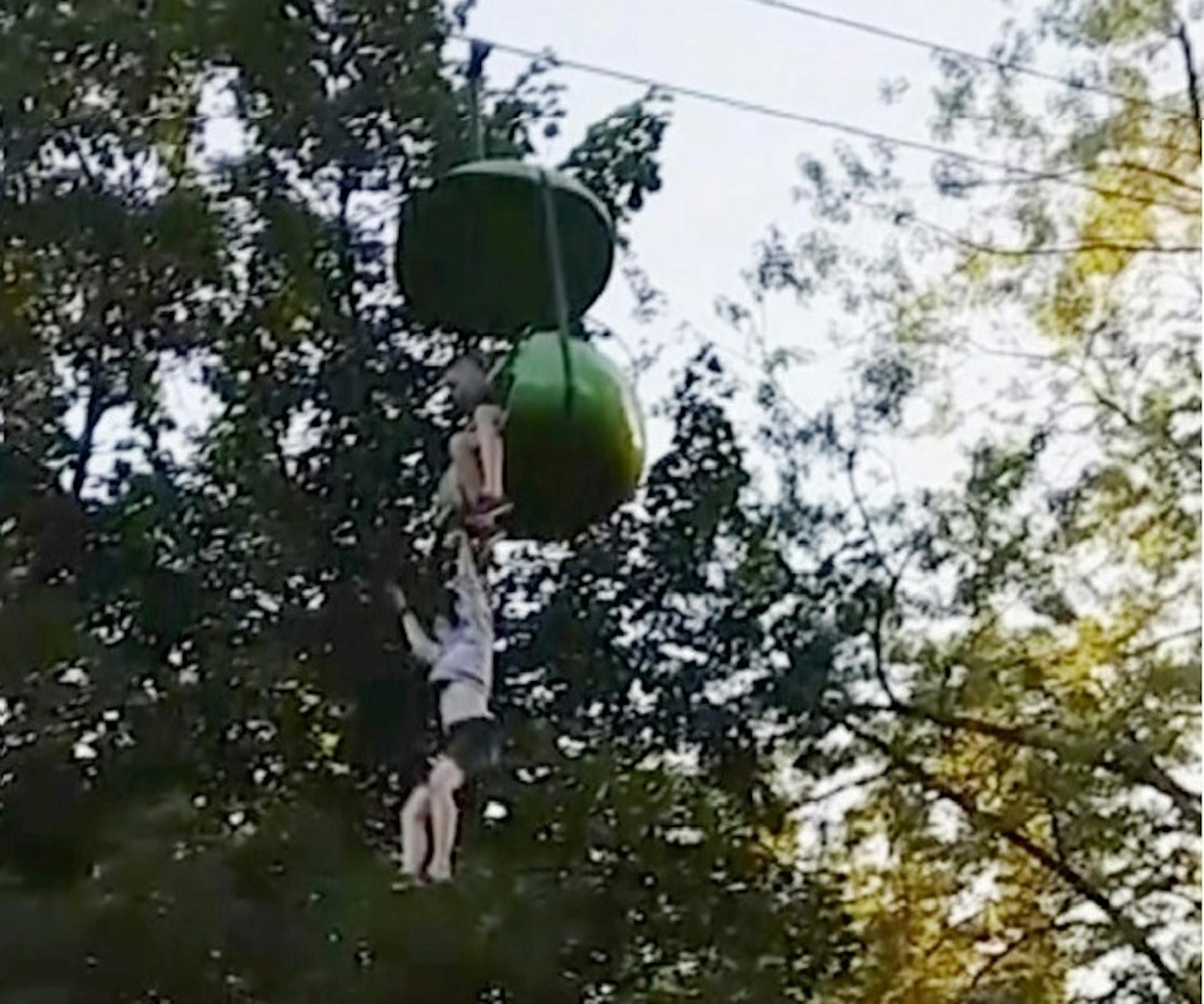 In this June 24, 2017, image made from a video provided by Leeann Winchell, a 14-year-old girl falls from an amusement park ride at Six Flags Great Escape Amusement Park in Queensbury, N.Y. After she lost her grip on the slow-moving gondola ride Saturday she fell into a crowd of park guests and employees gathered under the ride to catch her before she hit the ground.