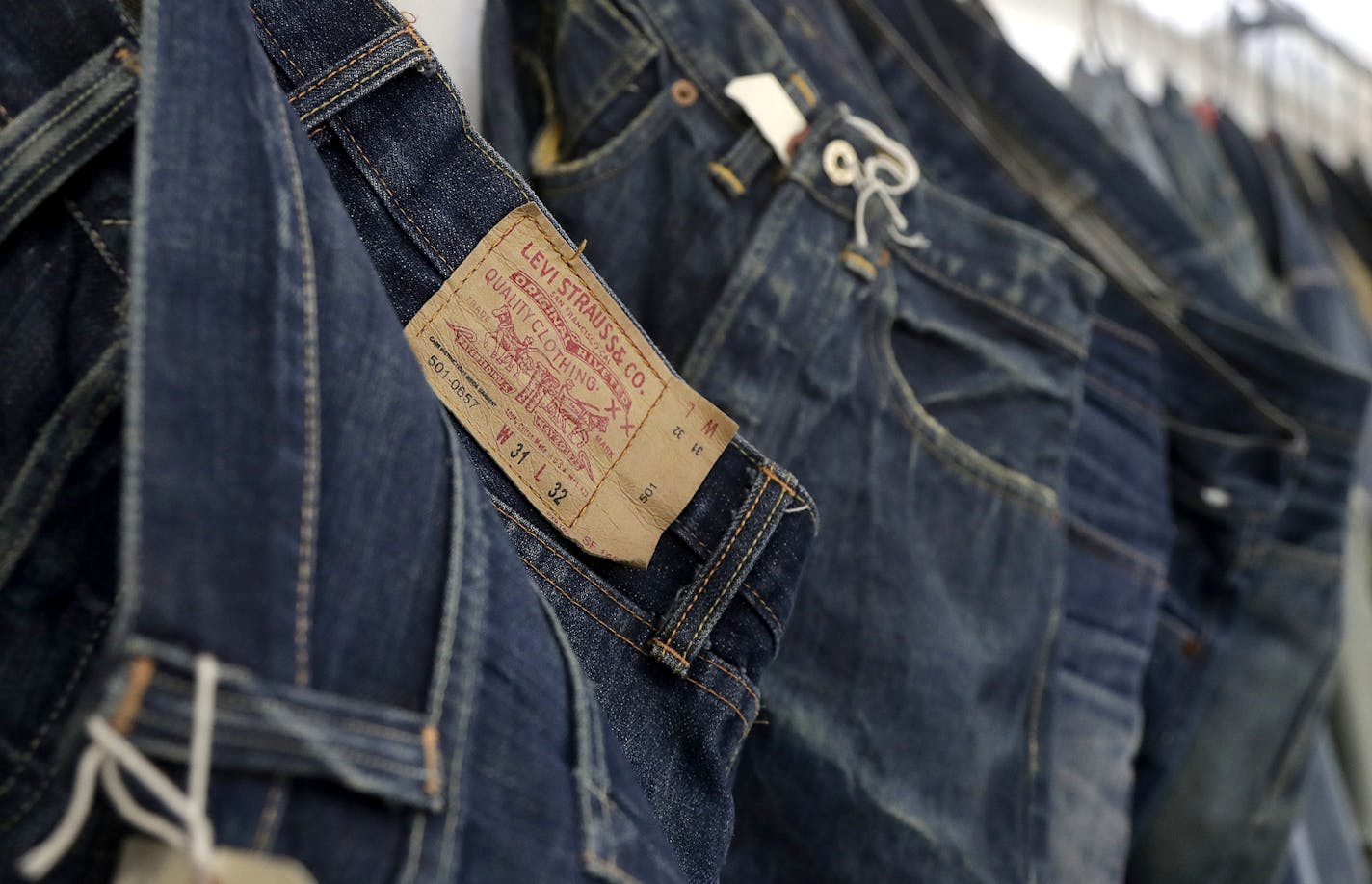 FILE- This Feb. 9, 2018 photo shows Levi's jeans hanging on a wall at Levi's innovation lab in San Francisco. Well-known jeans company Levi Strauss & Co. said Wednesday, Feb. 13, 2019, that it plans to raise about $100 million through an initial public offering. The number of shares to be offered and the price range has yet to be determined. (AP Photo/Jeff Chiu, File) ORG XMIT: NYBZ362