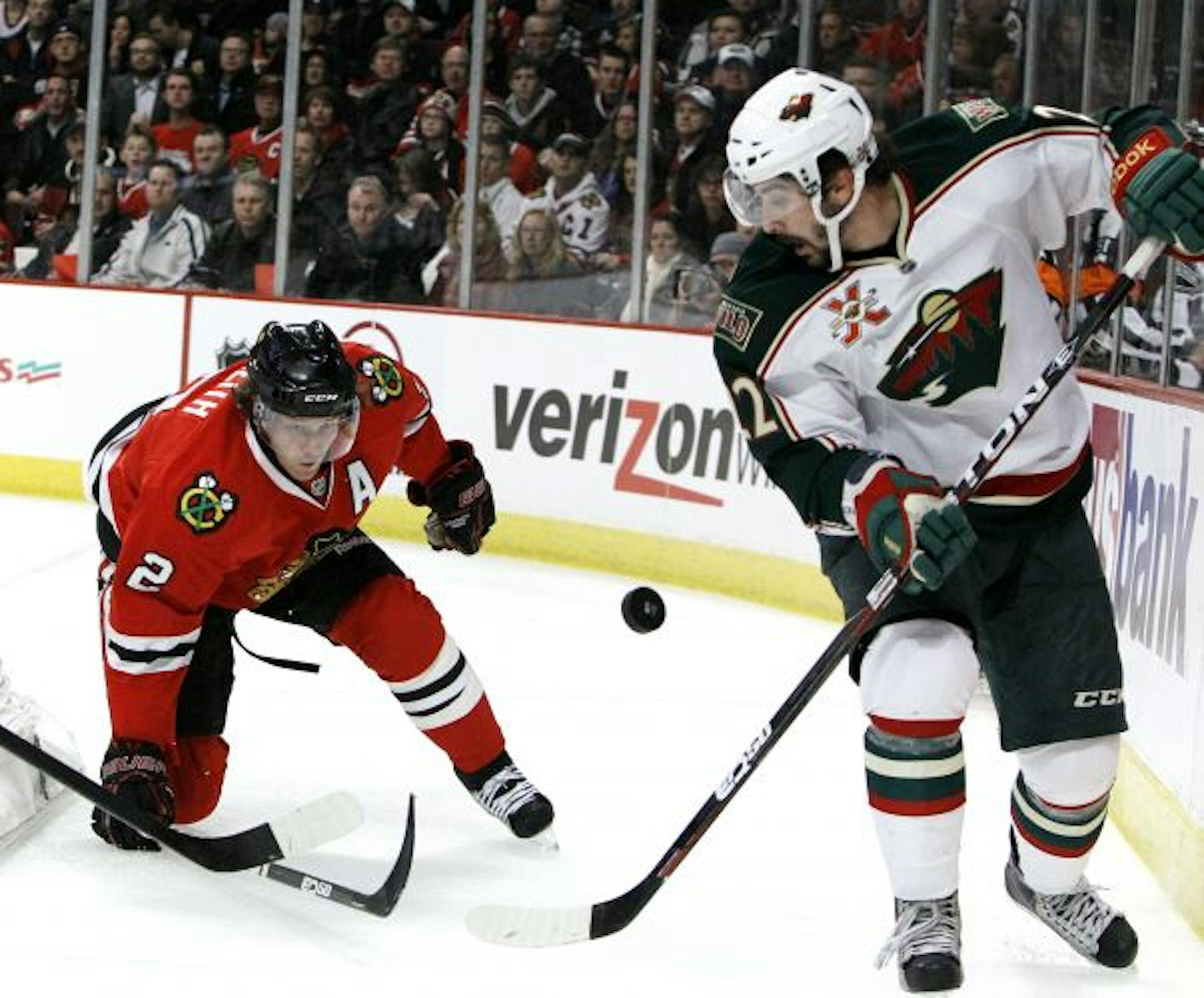 Chicago Blackhawks defenseman Duncan Keith, left, and Minnesota Wild right wing Cal Clutterbuck vie for a lose puck behind the Blackhawks' net during the first period of an NHL hockey game Wednesday, Feb. 16, 2011, in Chicago.