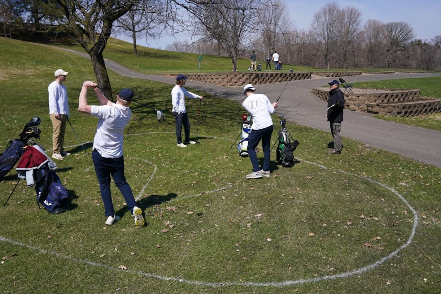 Friends, from left, Sam Rayner, Joey Parise, Peter Gorman and Eric Bradley stood in a pre-marked circle put out by course staff to encourage social distancing as they talked with starter Thomas Stopera, right, while waiting for the start of their round Saturday at Columbia Heights Golf Course.