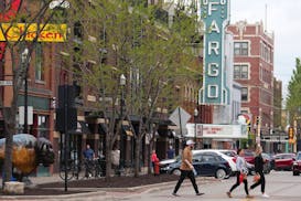 A sign for the Fargo Theatre, which first opened in 1926, hangs overhead as pedestrians walk through the downtown on a bright spring day on May 16 in 