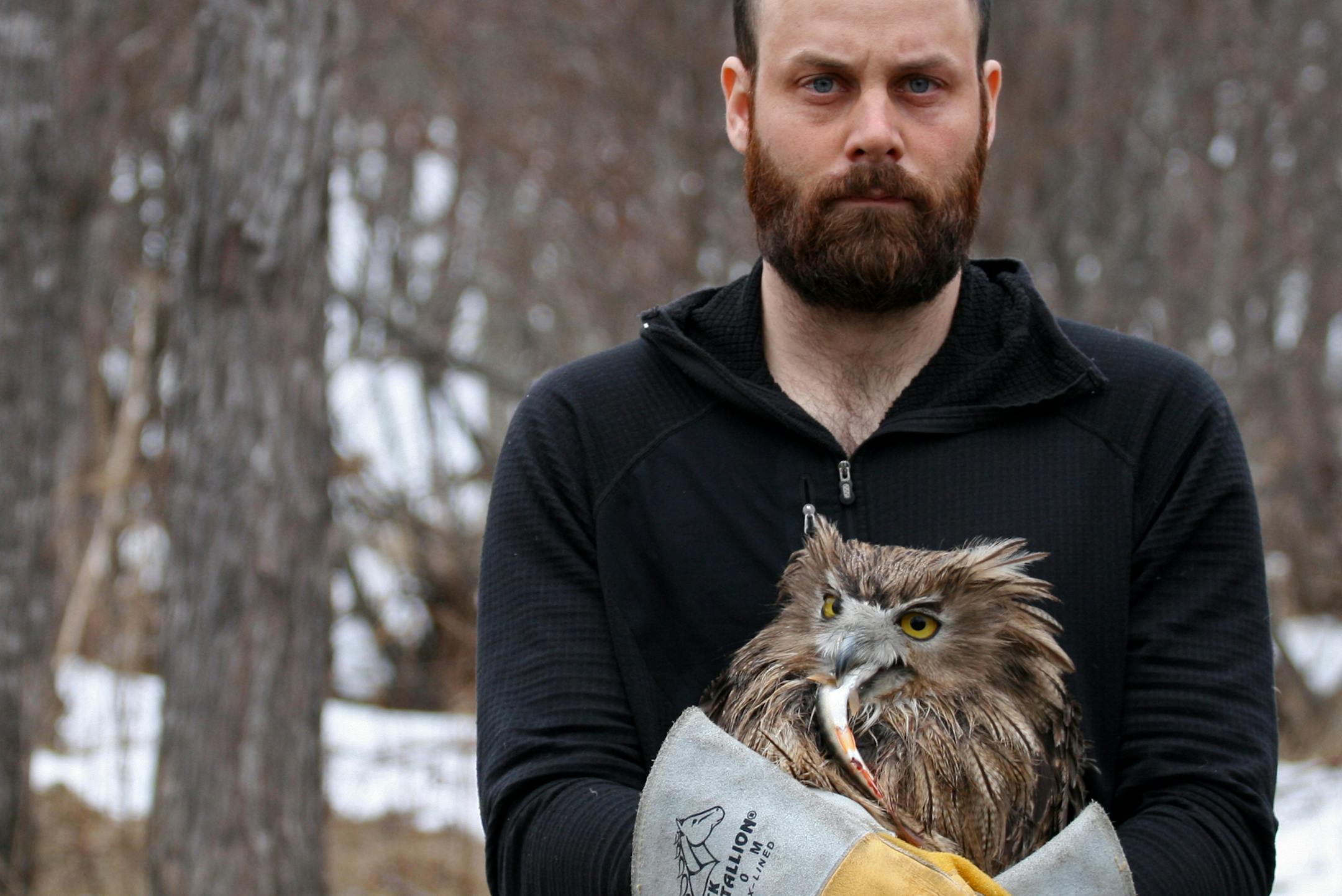 Jonathan C. Slaght and one of the female fish owls he caught and tracked in Russia. (The owl is holding a fish in its beak.) Photo by Sergey Avdeyuk