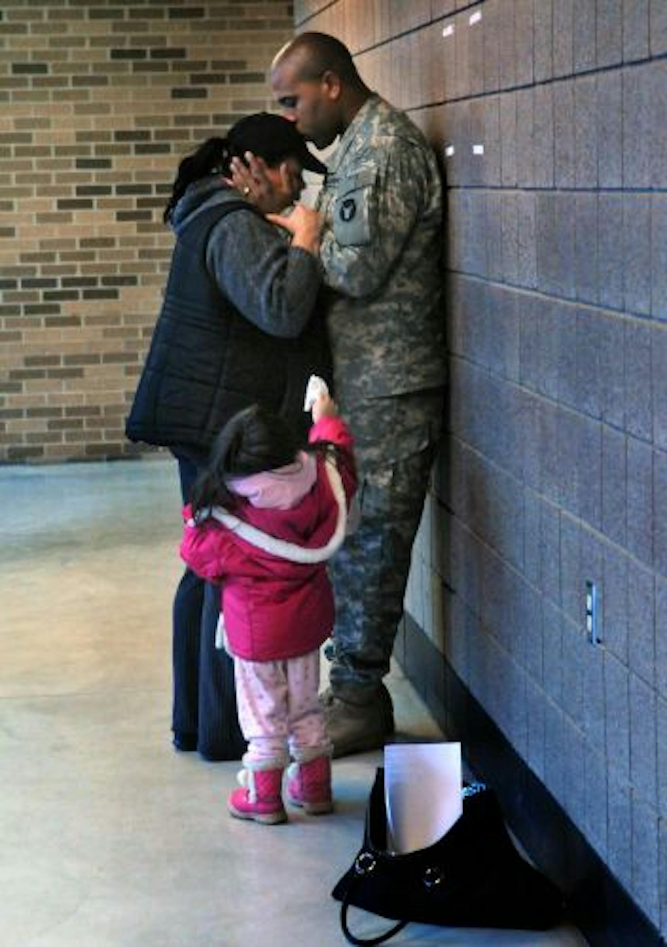 Terrance Jackson of Shakopee kisses his wife Holly a tearful goodbye as their 3 yr old daughter Destiny shares a tissue. The first group of 500 National Guard's 34th Red Bull Infantry Division members Departed from the Inver Grove Heights National Guard Armory.