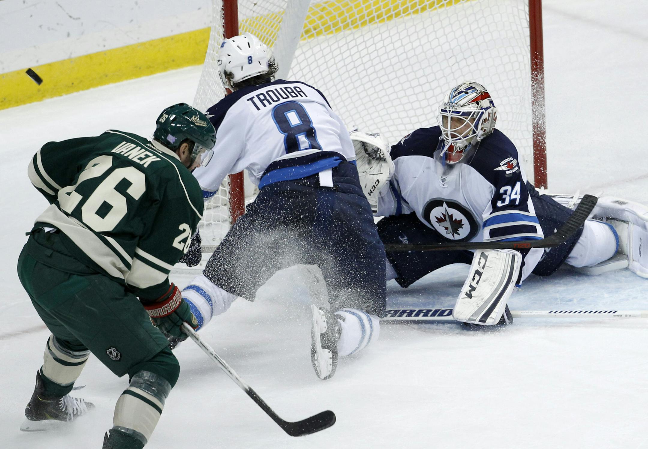 Winnipeg Jets goalie Michael Hutchinson (34) deflects a shot by Minnesota Wild left wing Thomas Vanek (26), of Austria, past Jets defenseman Jacob Trouba (8) during the third period of an NHL hockey game in St. Paul, Minn., Sunday, Nov. 16, 2014. The Wild won 4-3 in overtime. (AP Photo/Ann Heisenfelt)