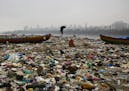 A fisherman walks on the shores of the Arabian Sea, littered with plastic bags and other garbage, in Mumbai, India, Sunday, Oct. 2, 2016. India is sch