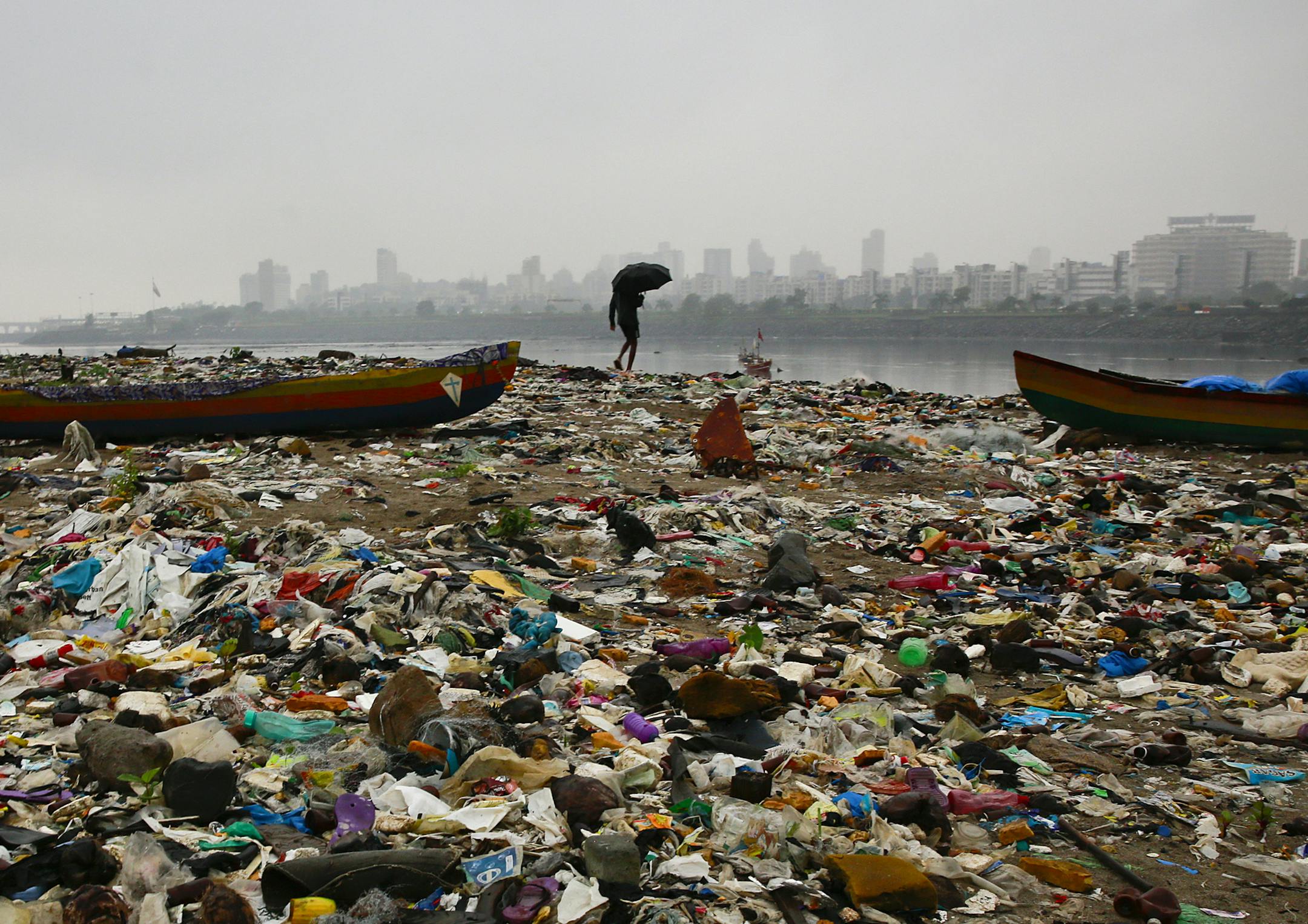 A fisherman walks on the shores of the Arabian Sea, littered with plastic bags and other garbage, in Mumbai, India, Sunday, Oct. 2, 2016. India is scheduled to deposit the ratification instruments of the Paris Agreement on Climate Change with the United Nations on Sunday, the anniversary of Mahatma Gandhi's birth, who believed in a minimum carbon footprint. India accounts for about 4.5 percent of emissions. (AP Photo/Rafiq Maqbool) ORG XMIT: DEL101