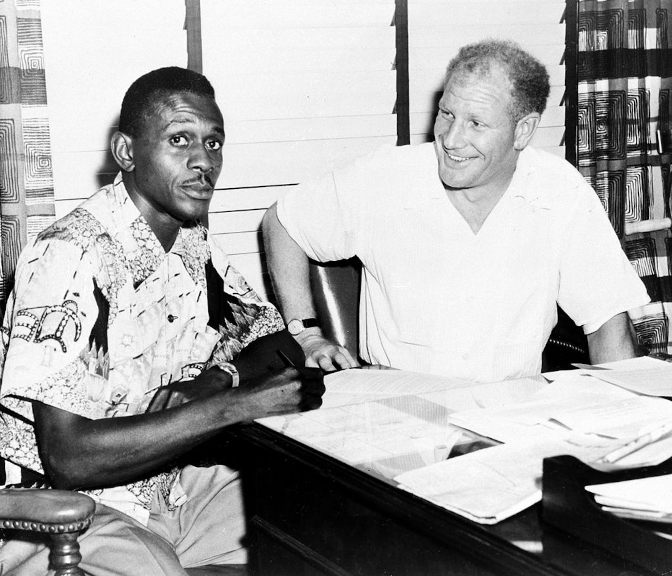 Satchel Paige, the ageless right-handed pitching star, signs the contract for his return to major league baseball, starting for the Browns, on July 18, 1951. Next to him is Bill Veeck, the new owner of the team.