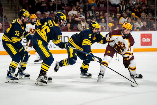 Gophers center Oliver Moore gets the attention of Michigan players -- from left, Kienan Draper, Seamus Casey and Tyler Duke -- during Minnesota's 6-2 