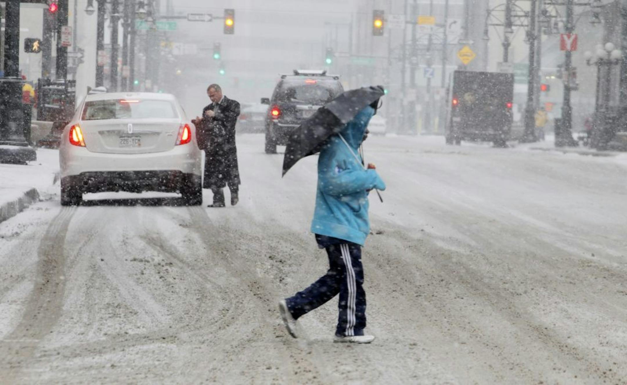 A man uses an umbrella to ward off snow as he crosses a street in Denver's financial district on Tuesday, April 9, 2013. A blizzard forecast for the area did not materialize. Instead as much as four inches of snow could fall on the Mile High City.