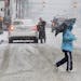 A man uses an umbrella to ward off snow as he crosses a street in Denver's financial district on Tuesday, April 9, 2013. A blizzard forecast for the a