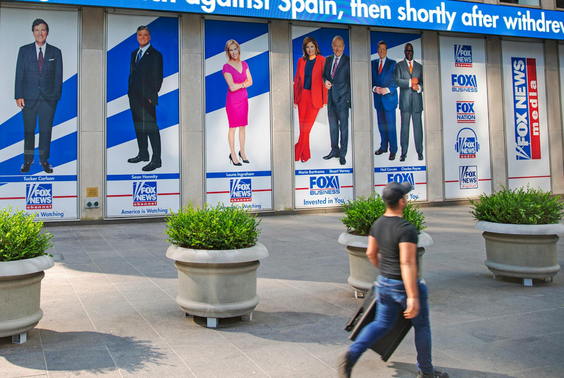 FILE - Images of Fox News personalities, from left, Tucker Carlson, Sean Hannity, Laura Ingraham, Maria Bartiromo, Stuart Varney, Neil Cavuto and Charles Payne appear outside News Corporation headquarters in New York on July 31, 2021.