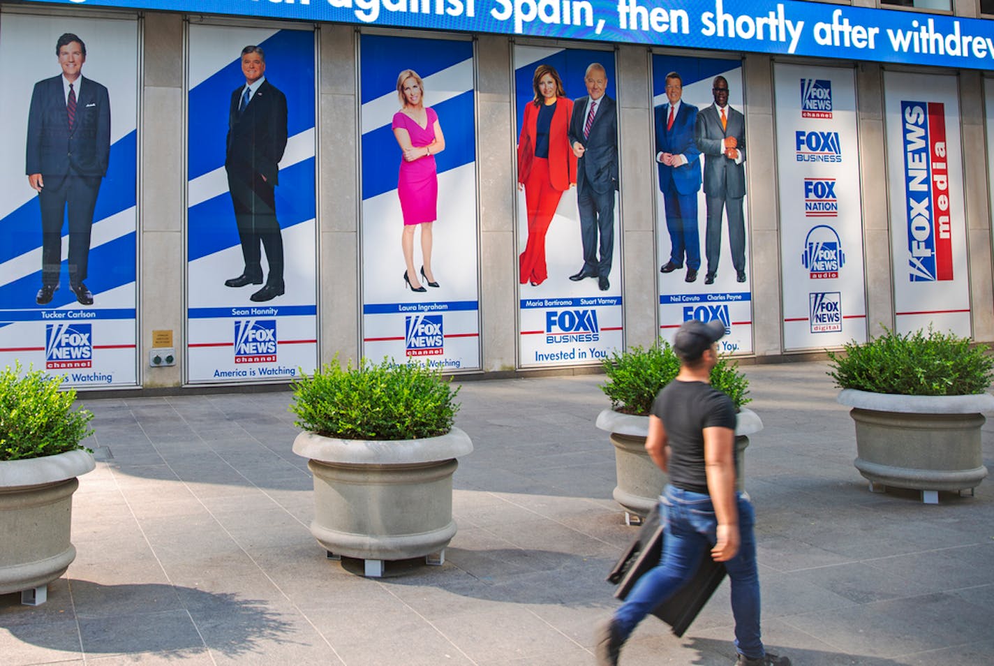 FILE - Images of Fox News personalities, from left, Tucker Carlson, Sean Hannity, Laura Ingraham, Maria Bartiromo, Stuart Varney, Neil Cavuto and Charles Payne appear outside News Corporation headquarters in New York on July 31, 2021.