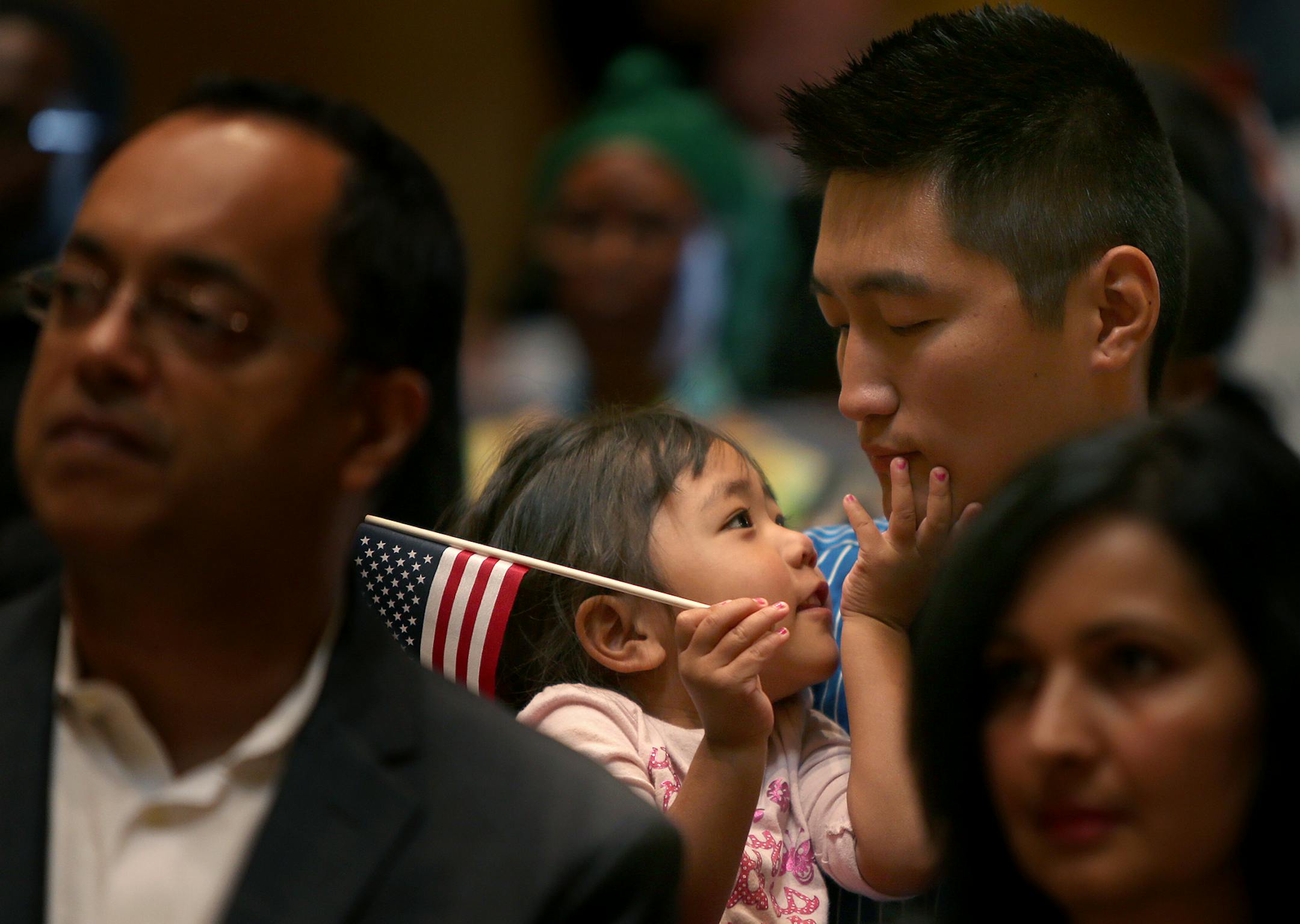 Lhanzay Gansukh, 3, kept close to her father Gatsu Gansukh of Mongolia, as he joined others at the State Capitol to become a Naturalized Citizen, Tuesday, September 17, 2013 in St. Paul, MN. The U.S. Citizenship and Immigration Services (USCIS) welcomed 26 people to be Naturalized Citizens in the Minnesota State Capitol Rotunda During Constitution Day and Citizenship Day Celebration. More than 18,000 people will become U.S. citizens during approximately 180 naturalization ceremonies across the c