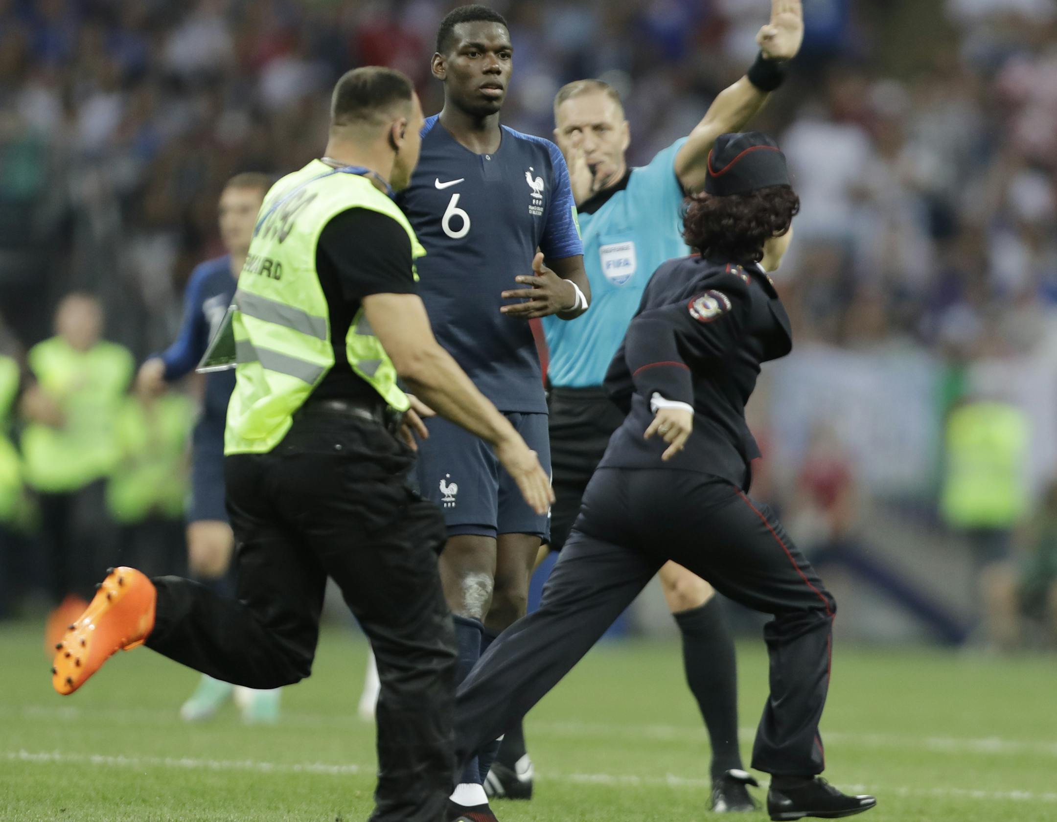 France's Paul Pogba watches a security staffer chasing a pitch invader during the final match between France and Croatia at the 2018 soccer World Cup in the Luzhniki Stadium in Moscow, Russia, Sunday, July 15, 2018. (AP Photo/Natacha Pisarenko)