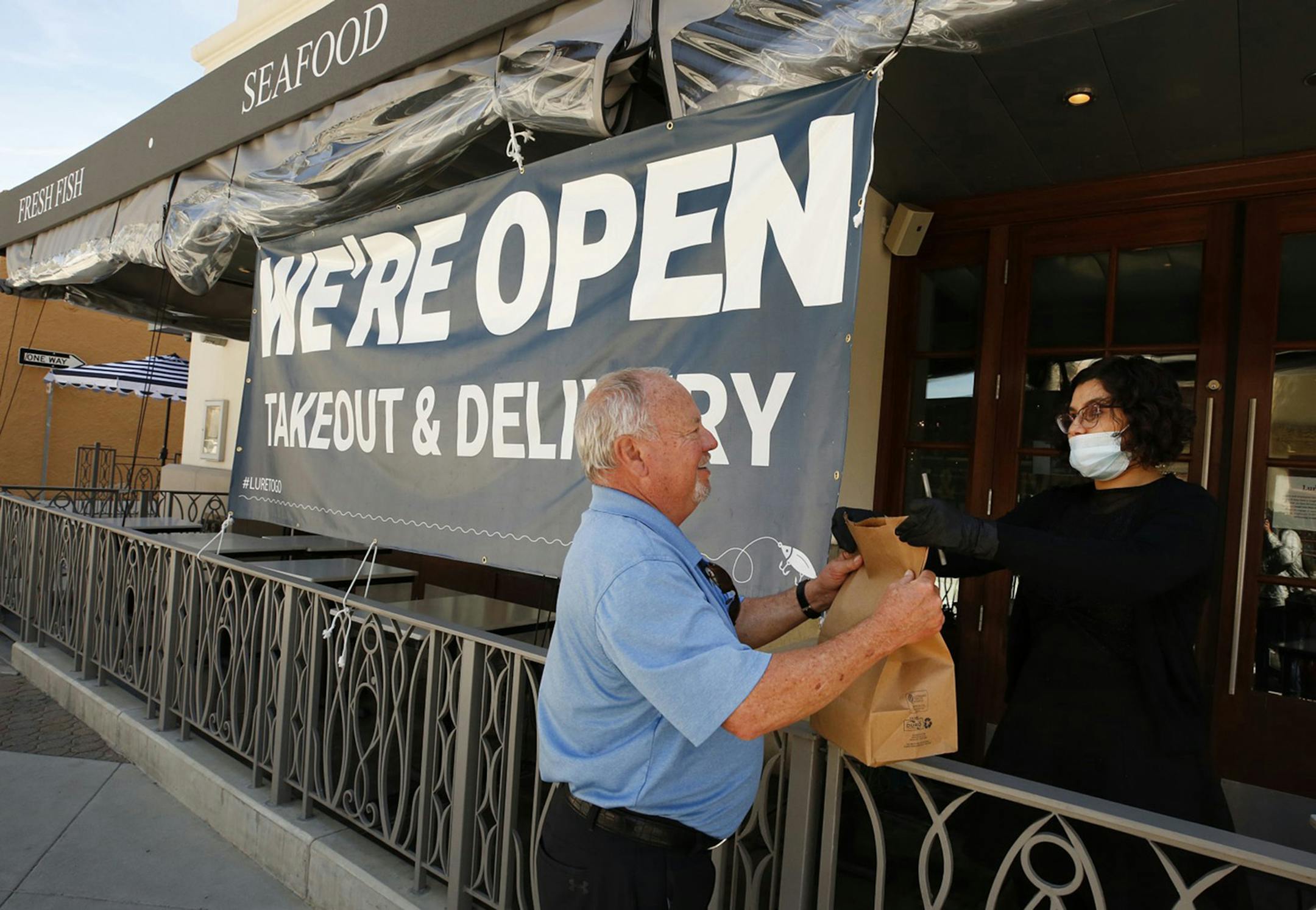 Greg Thomas picks up his lunch from Samantha Madec at Lure Fish House on South California Street in downtown Ventura, Calif. on Wednesday, April 22, 2020 as Ventura County modified its stay-at-home order to permit some businesses to reopen and some gatherings to take place for the first time since the restrictions were issued to fight the spread of the coronavirus COVID-19. (Al Seib/Los Angeles Times/TNS) ORG XMIT: 1644123